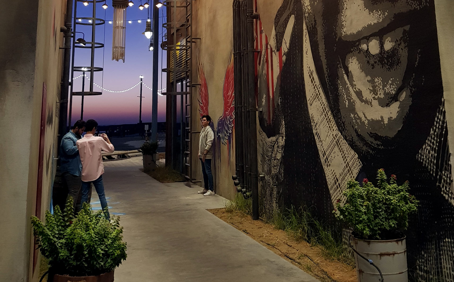 People taking photos at La Mer by the wall art at sunset