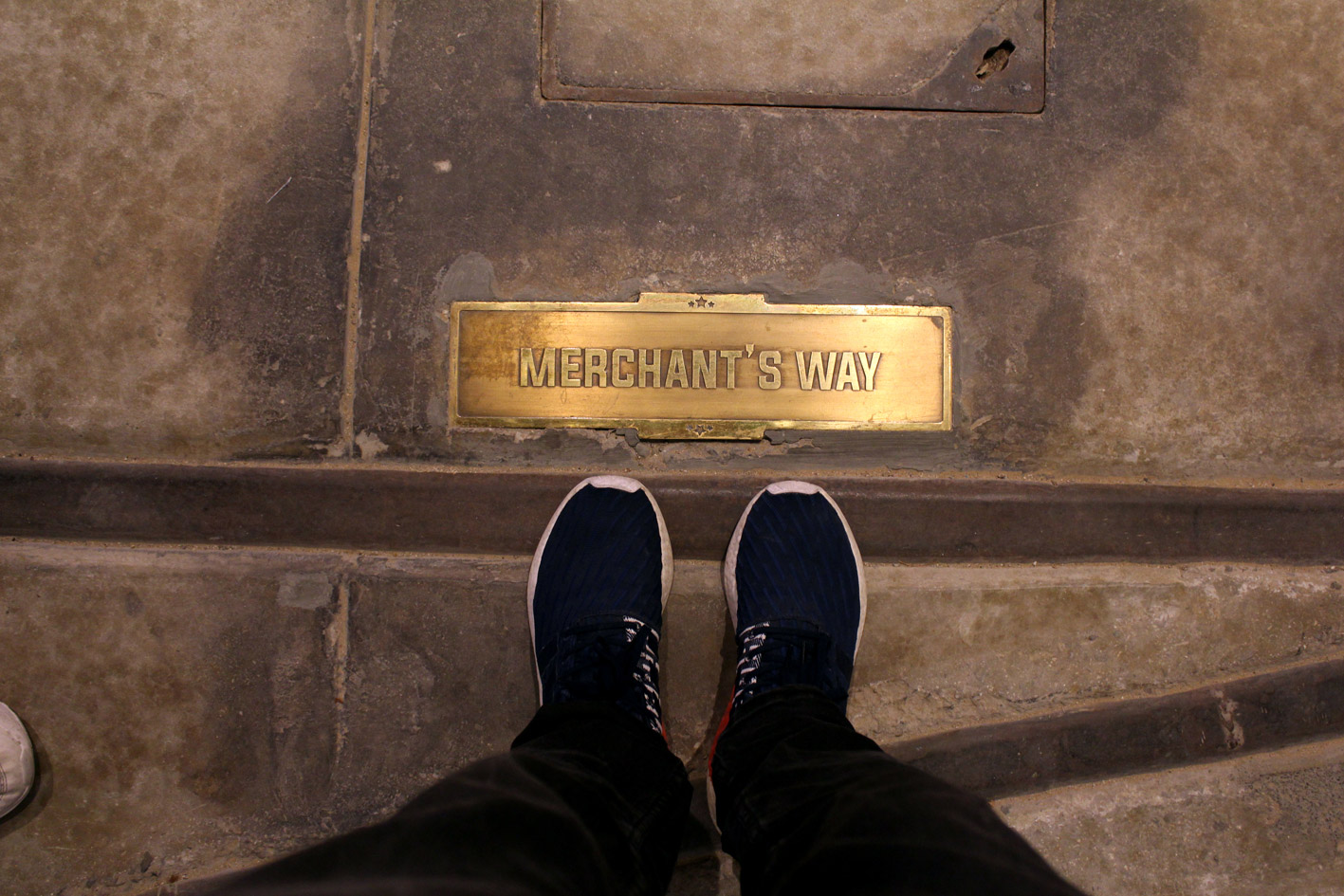 Man wearing sneakers and taking a photo next to a gold inlaid plaque saying picturehouse at La Mer, designed by LIMAH
