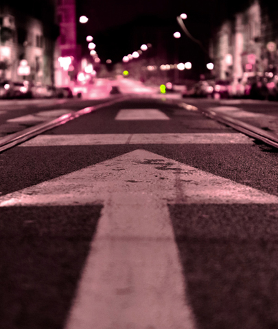 Night shot of arrow sign painted on the road.